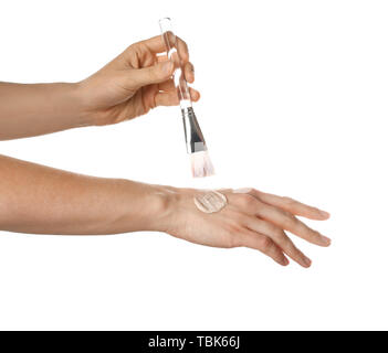 Donna applicazione di scrub di zucchero su mani contro uno sfondo bianco Foto Stock