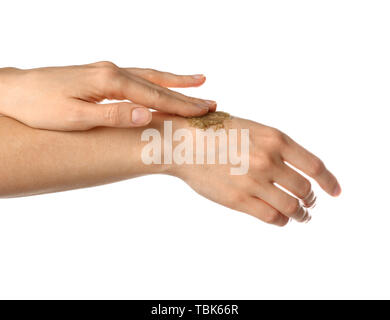 Donna applicazione di scrub di zucchero su mani contro uno sfondo bianco Foto Stock