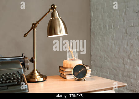 Vecchia macchina da scrivere con la luce dorata e articoli di cancelleria sul tavolo di legno in camera Foto Stock