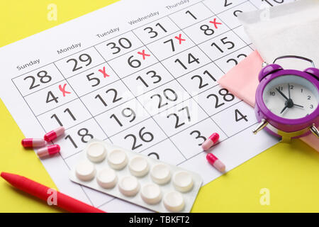 Calendario Mestruale con le pillole e sveglia sul colore di sfondo Foto Stock