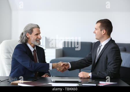 Imprenditore maturo si stringono la mano con il giovane collega in ufficio Foto Stock