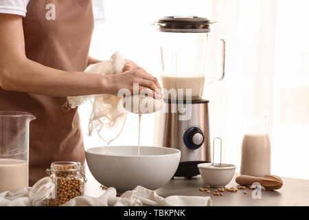 Donna che fa il latte di soia in cucina Foto Stock