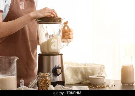 Donna che fa il latte di soia in cucina Foto Stock