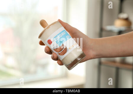 Donna che mantiene un vasetto di olio di noce di cocco in cucina Foto Stock
