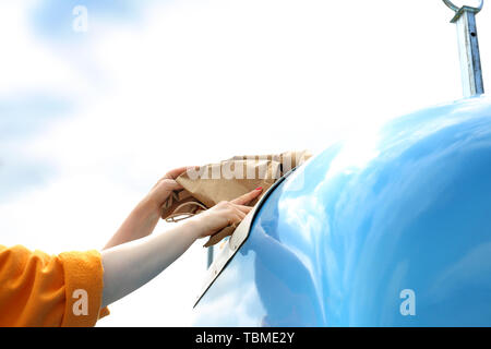 Riciclaggio di una donna getta lo spreco di carta in un contenitore blu Foto Stock