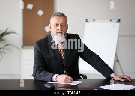 Imprenditore maturo seduta a tavola in office Foto Stock