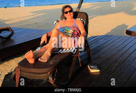 Donna in rilassanti lettini Nilavelli beach, vicino a Trincomalee, provincia Orientale, Sri Lanka, Asia Foto Stock