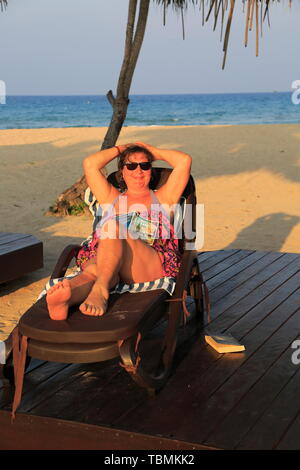 Donna in rilassanti lettini Nilavelli beach, vicino a Trincomalee, provincia Orientale, Sri Lanka, Asia Foto Stock