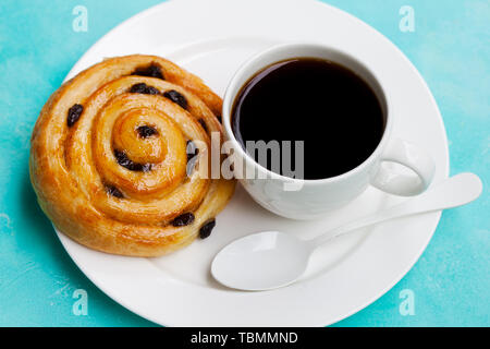 Fresca pasticceria danese con uvetta con una tazza di caffè nero su blu sullo sfondo della tabella Foto Stock