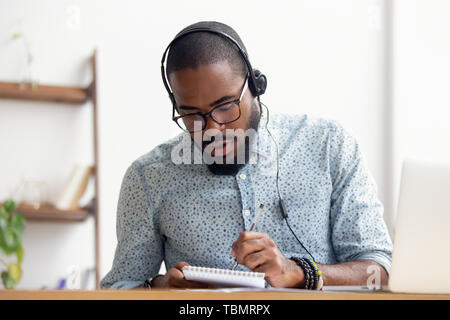 African American uomo nelle cuffie prendere corso di e-learning in ufficio Foto Stock