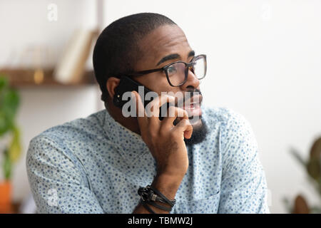 Chiudere fino Afro-dipendente americano parlando al telefono sul posto di lavoro in ufficio Foto Stock