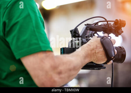 Videografo le riprese di un film o di un programma televisivo in un monolocale con una fotocamera professionale, backstage Foto Stock