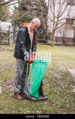 Uomo maturo con un piccolo batuffolo durante le pulizie di primavera nel giardino Foto Stock