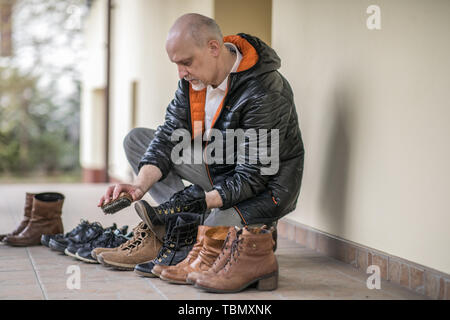 L'uomo è di lucidatura delle scarpe sulla terrazza durante il tempo di primavera Foto Stock