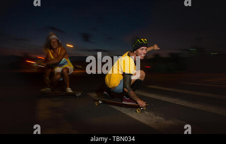 I giovani skateboarders cavalcano gli skateboard di notte Foto Stock