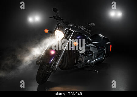 Moto blu su sfondo scuro con luce da dietro e fumo Foto Stock