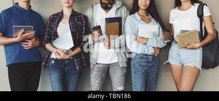 Teen gli studenti titolari di libri e gadget in mani Foto Stock