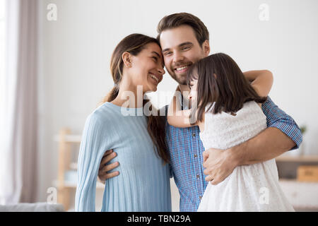 Uomo felice abbraccio bella moglie e figlia in salotto Foto Stock