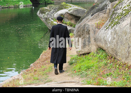 Ebreo Hasidic ragazzo in abiti neri a piedi nel parco di Uman, Ucraina, il tempo dell'anno ebraico, religiosa ebrea, ortodossa Foto Stock