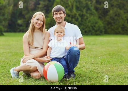 La famiglia felice insieme nel parco d'estate. Madre, padre e figlio figlio in natura. Foto Stock