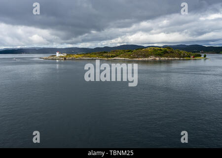 Una piccola e pittoresca isola con un faro visto da una nave da crociera nei fiordi norvegesi Foto Stock
