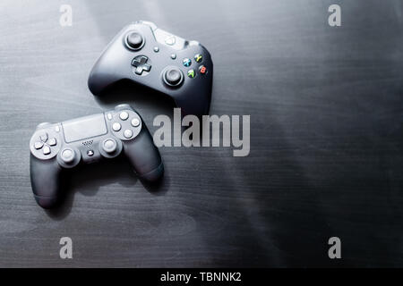 Xbox e Playstation controller sedeva accanto a ogni altro su sfondo scuro Foto Stock