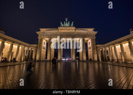 Pochi turisti presso la famosa e neoclassico illuminato Porta di Brandeburgo (Brandenburger Tor) di Berlino, Germania, al tramonto. Foto Stock