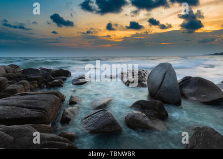 Il mare e la roccia nei colori del tramonto foto con outdoor e bassa illuminazione scuro seascape. Foto Stock