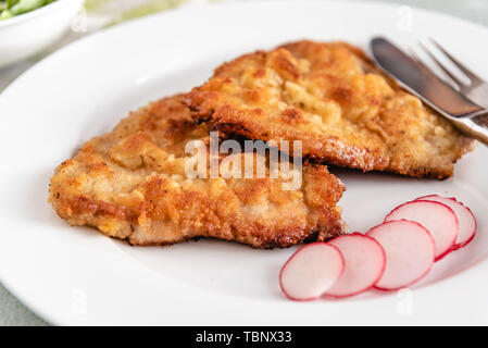 Maiale fritto chop nel pangrattato servita con ravanelli. Foto Stock