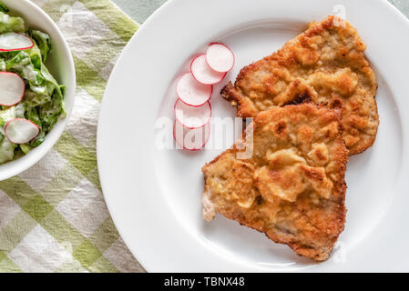 Maiale fritto chop nel pangrattato servita con ravanelli. Foto Stock