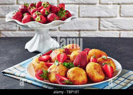 Close-up di cottage dolci di ricotta con le fragole su una piastra su un tavolo di calcestruzzo. coppa di frutta con fragole fresche a sfondo nella parte anteriore di un Foto Stock