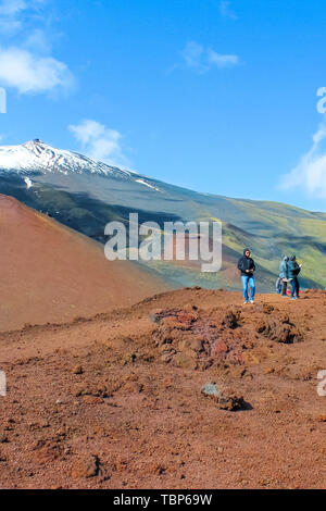 Il monte Etna, Sicilia, Italia - 9 Aprile 2019: coppia di turisti in piedi sui crateri Silvestri affacciato sulla cima del vulcano Etna. La neve sulla cima della montagna. Destinazione popolare. Foto Stock