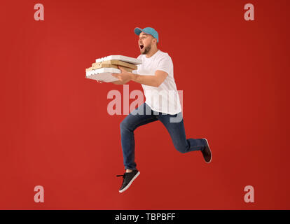 Jumping corriere maschio con scatole per pizza sul colore di sfondo Foto Stock