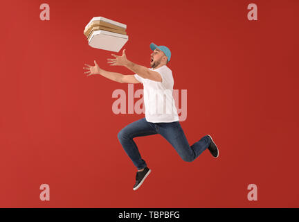 Jumping corriere maschio con scatole per pizza sul colore di sfondo Foto Stock