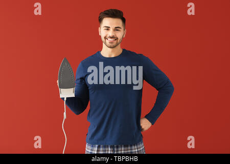 Giovane uomo con il ferro sul colore di sfondo Foto Stock