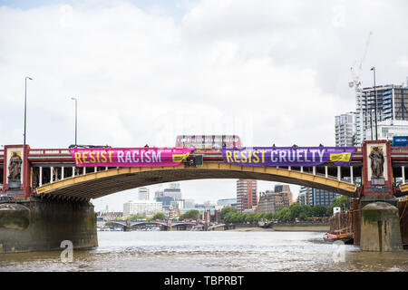 Londra, Regno Unito. Il 3 giugno, 2019. Due dei cinque colori vivaci dei banner recanti gli slogan "Resistere Trump', 'resistere sessismo', 'resistere al razzismo", "resistere odio' e 'resistere alla crudeltà' sono sceso da Vauxhall Bridge in vista dell'ambasciata Usa dagli attivisti di Amnesty International all'inizio del presidente Donald Trump's tre giorni di visita di Stato nel Regno Unito. Amnesty International ha scritto al Primo Ministro Theresa Maggio ha scritto al Theresa Maggio di incitarla a sollevare le questioni relative ai diritti umani direttamente con il Presidente degli Stati Uniti. Credito: Mark Kerrison/Alamy Live News Foto Stock