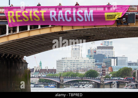 Londra, Regno Unito. Il 3 giugno, 2019. Uno dei cinque colori vivaci dei banner recanti gli slogan "Resistere Trump', 'resistere sessismo', 'resistere al razzismo", "resistere odio' e 'resistere alla crudeltà' è sceso da Vauxhall Bridge in vista dell'ambasciata Usa dagli attivisti di Amnesty International all'inizio del presidente Donald Trump's tre giorni di visita di Stato nel Regno Unito. Amnesty International ha scritto al Primo Ministro Theresa Maggio ha scritto al Theresa Maggio di incitarla a sollevare le questioni relative ai diritti umani direttamente con il Presidente degli Stati Uniti. Credito: Mark Kerrison/Alamy Live News Foto Stock