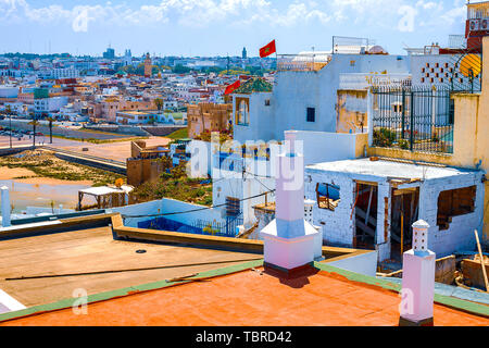 Il tetto di un edificio tradizionale con un camino e un tubo che si affaccia sull'oceano e la linea di costa nel quartiere Medina nella città di Rabat, Moro Foto Stock