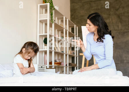 Madre scolding suo naughty little figlia a casa Foto Stock