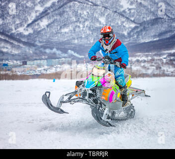 La Kamchatka, Russia - 10 APR 2018: Kamchatka, il festival "oggi". Atleta su una motoslitta in movimento nella foresta invernale sulla concorrenza in m Foto Stock