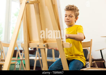 Ragazzo una buona sensazione. Ragazzo di talento una buona sensazione e occupato mentre la pittura alla scuola d'arte Foto Stock