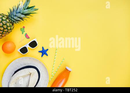 Vacanze estive dello sfondo. Cappello di paglia, bianco occhiali da sole, frutti tropicali freschi succhi di frutta e cocktail accessori su sfondo giallo. Spazio di copia, fla Foto Stock