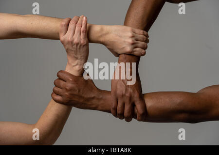 Gare uniti contro la discriminazione e il razzismo. Il nero americano africano e Caucasico mani tenendo insieme nel mondiale di unità e di amore razziale e underst Foto Stock