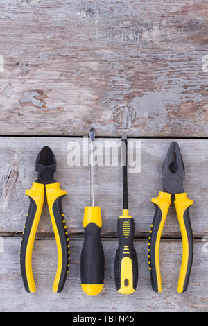 Strumenti di costruzione su sfondo di legno. Pinze e cacciaviti su rustiche tavole. Vista da sopra con copia spazio. Foto Stock