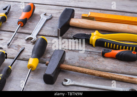 Set di strumenti di costruzione su sfondo di legno. Parte del kit strumenti che comprendono martelli, cacciaviti, pinze, chiavi e un righello. Foto Stock