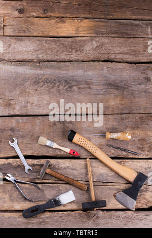 Diversi utensili a mano per la costruzione, vista dall'alto. Il vecchio gli strumenti a mano impostare compresi ax, martelli, cacciavite, chiavi e pinze. In stile vintage. Foto Stock