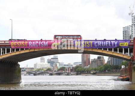 Attivista di Amnesty International distendere anti-Trump banner da Vauxhall Bridge in vista dell'Ambasciata degli Stati Uniti a Londra centrale, il giorno uno di noi presidente Donald Trump's visita di Stato nel Regno Unito. Foto Stock