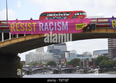 Attivista di Amnesty International distendere anti-Trump banner da Vauxhall Bridge in vista dell'Ambasciata degli Stati Uniti a Londra centrale, il giorno uno di noi presidente Donald Trump's visita di Stato nel Regno Unito. Foto Stock