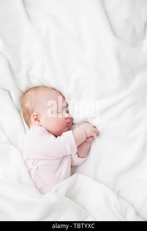 Il bambino dorme, 3 mesi di età bambino in panno rosa dormire su una coltre bianca, Bambino addormentato nel letto Foto Stock