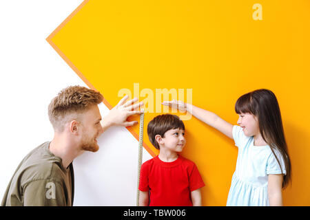 Il padre e il suo piccolo bambini altezza di misurazione vicino a parete Foto Stock